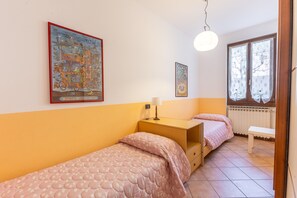 A bedroom with two beds, a bedside table, a lamp, and two wall-mounted pictures. - Tina Home Lake View (Garda)