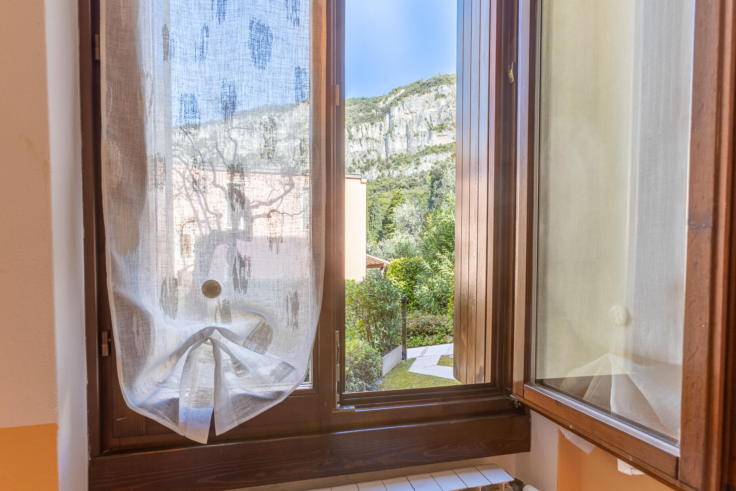 Ein Fenster mit Blick auf eine gebirgige Landschaft und ein Gebäude.