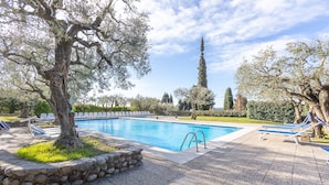 A swimming pool with lounge chairs and a stone border. - Tina Home Lake View (Garda)
