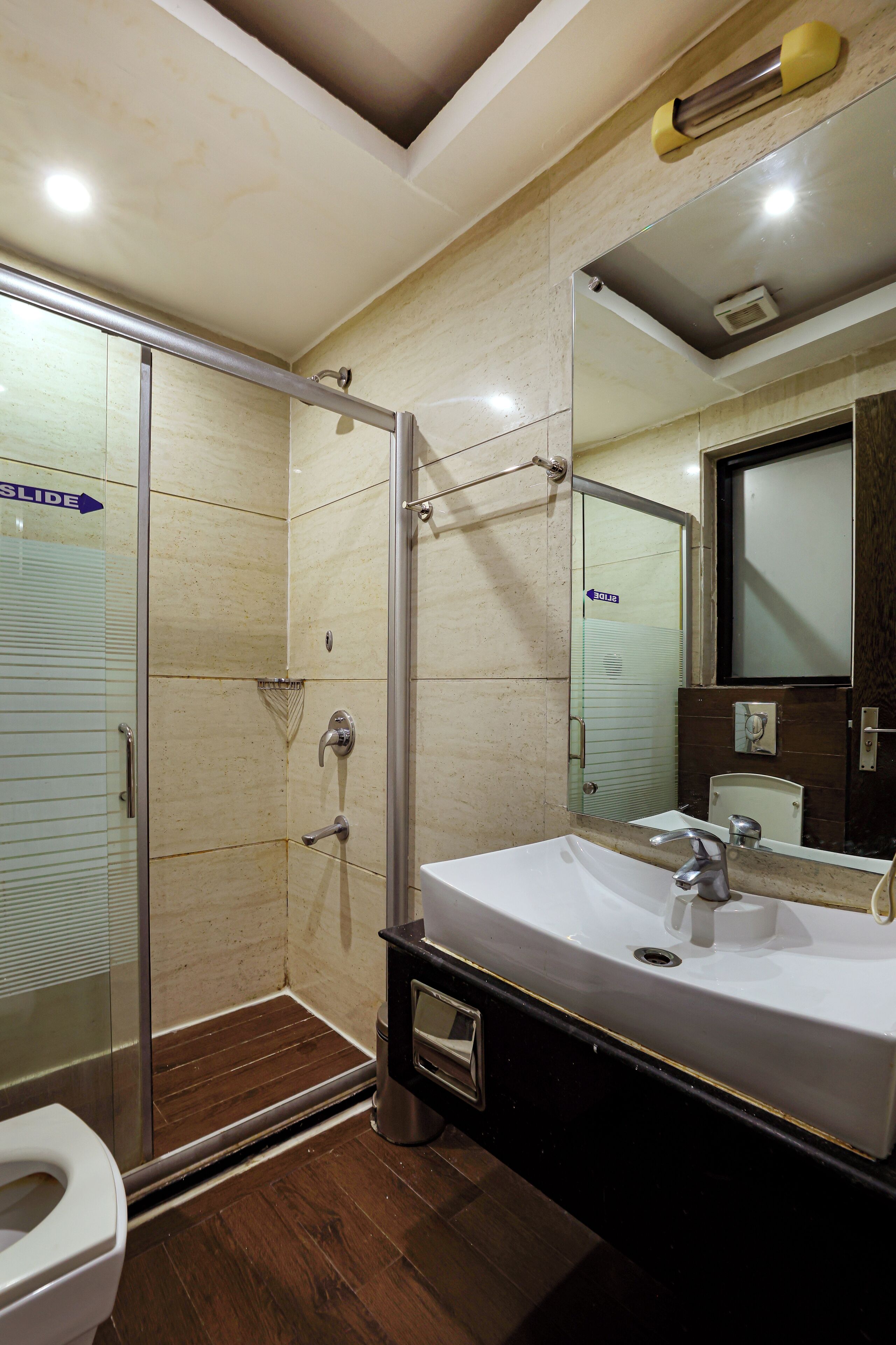 A modern bathroom with a glass shower enclosure, a sink, and a toilet.