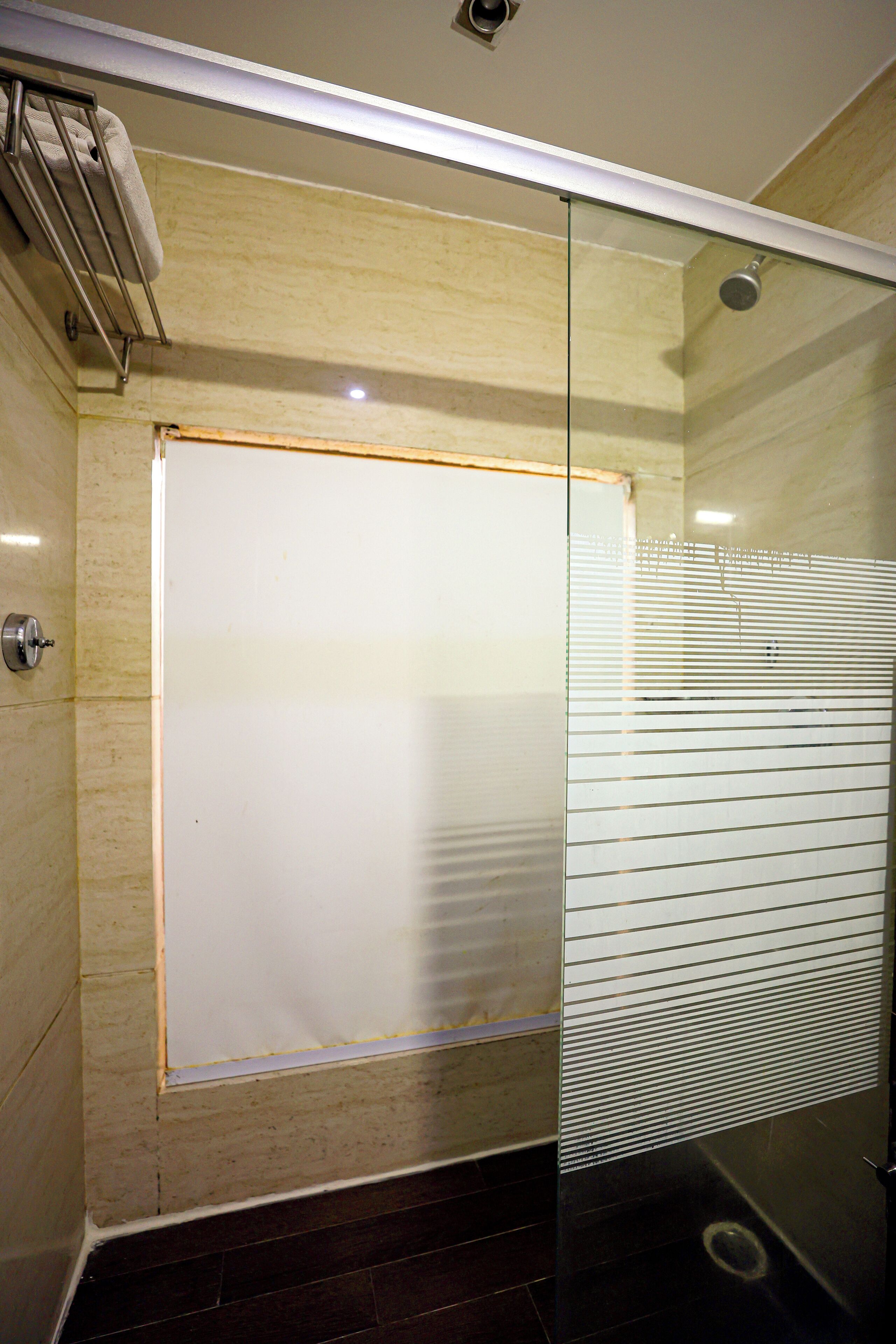 Une salle de bain moderne dotée d’une cabine de douche en verre, d’un porte-serviettes et d’un pommeau de douche bien visible.