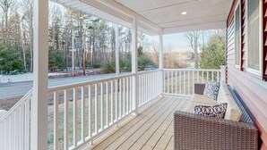 A covered porch with a wooden floor, white railings, and wicker furniture. - Enchanting 3BR Farmhouse Retreat  Nature Getaway (Gorham)