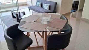 A modern dining area with a glass table, black chairs, and a glass bowl centerpiece. - Beautiful apartment with balcony facing the sea (Lima)