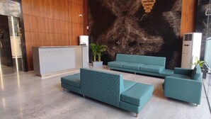 A modern lobby with teal seating, a reception desk, and a large abstract wall mural. - HOTEL VIVOTEL (Surat)