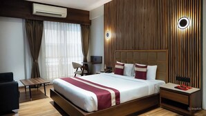 A modern hotel room with a large bed, a desk, a chair, and a nightstand. - HOTEL VIVOTEL (Surat)