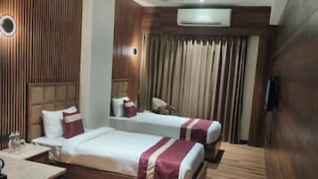 Habitación de hotel con dos camas, una mesita, una silla, aire acondicionado y televisión.