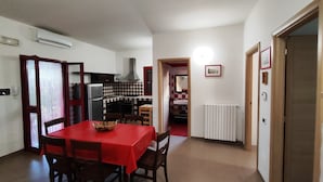 Een kleine keuken met een koelkast, fornuis en een rode geruitte spatwand.