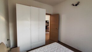Een slaapkamer met een bed, een kledingkast en een deur naar een keuken.