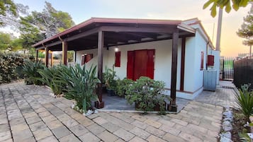 Enjoy a peaceful retreat on this charming property with a covered porch, potted plants, and a garden.