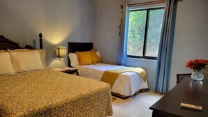 Habitación de hotel con dos camas, una mesita de noche, un escritorio y una ventana con cortinas.