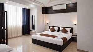 Een moderne hotelkamer met een groot bed, nachtkastjes, een airconditioning en uitzicht door het raam.