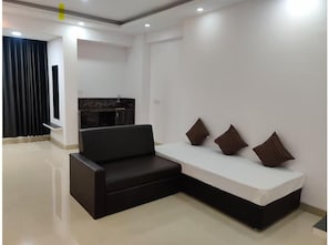 Ein modernes Wohnzimmer mit einem schwarzen Ecksofa, einem weißen Sofa und drei Zierkissen.