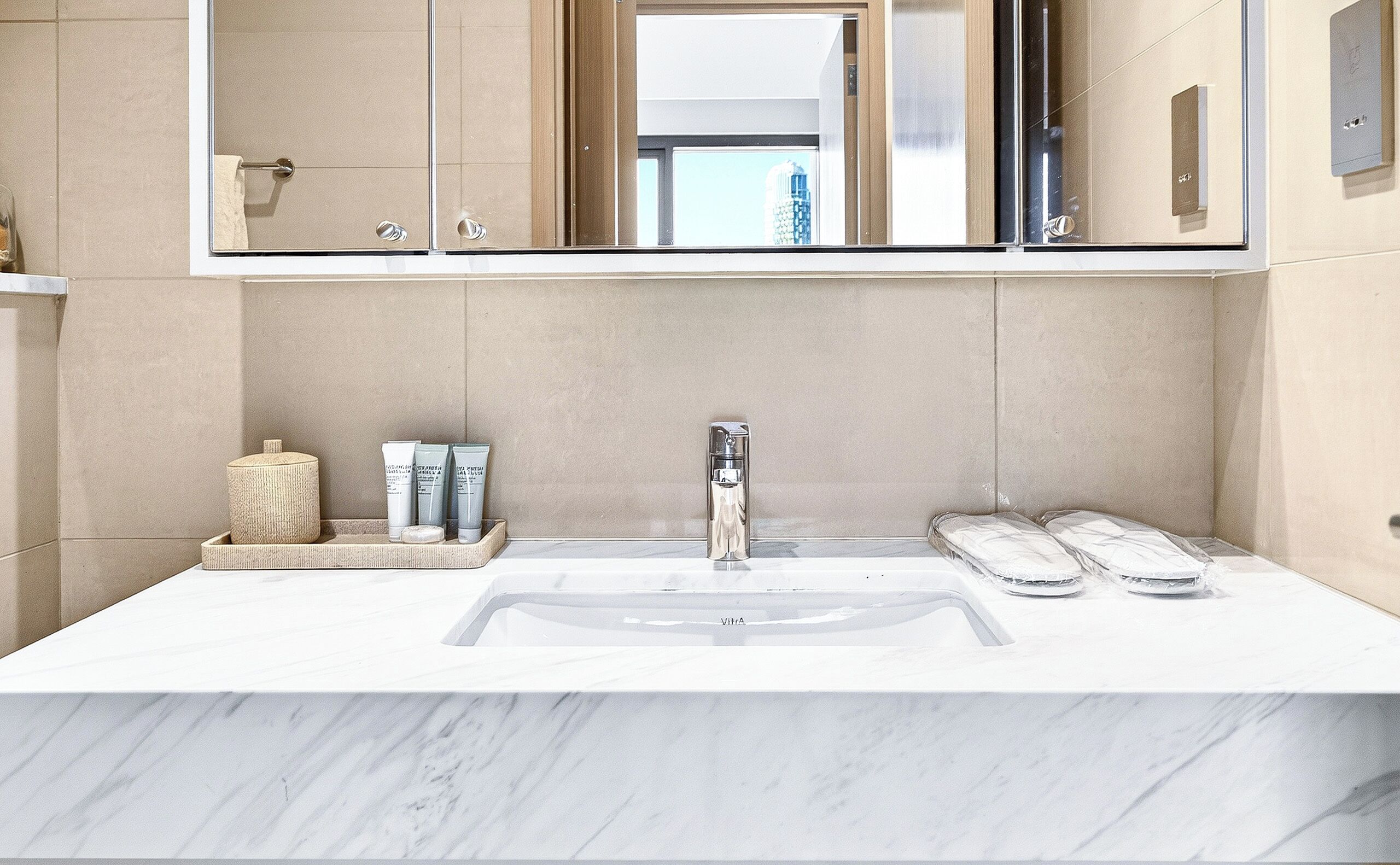 A bathroom with a large mirror, a sink, and toiletries on a tray.