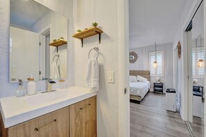Ein modernes Badezimmer mit einem weißen Waschbecken, Holzschränken und einem großen Spiegel.