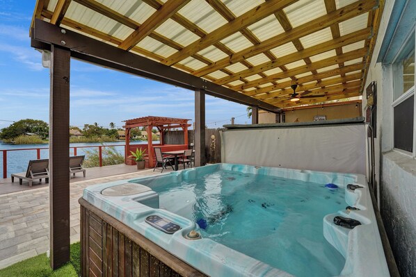 Ein Whirlpool unter einer Holzpergola mit Seeblick.