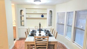 A dining area with a wooden table and chairs, a chandelier, and a view of the kitchen through an archway. - Country Home in the City with and Acre of Land (Zephyrhills)