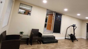A spacious living area with a high ceiling, a treadmill, and a sliding glass door leading to a balcony. - Country Home in the City with and Acre of Land (Zephyrhills)