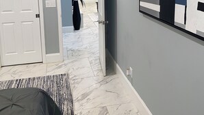 A modern hotel room with a marble floor, a bed, a large abstract painting, and a hallway leading to another room. - Charming 2-bedroom house with AC, WiFi in delightful Atlanta (Atlanta)