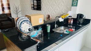 A modern kitchen with a black countertop, white cabinets, a built-in sink, and a coffee maker. - Beach house in Arraial do Cabo, Summer Beach condominium. Also through other platforms (Arraial do Cabo)