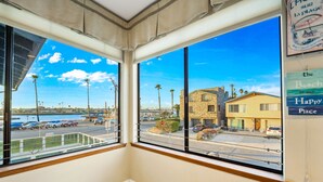 A room with large windows overlooking a beach and a parking area. - 25% Off Sept 10-12, Walk 2 Beach, Private Jacuzzi! (Oxnard)