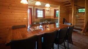 A wooden cabin interior with a dining table, chairs, a sofa, and a staircase. - Attractive Swedish group accommodation by the meadow (Soest)