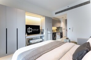 A modern hotel room with a bed, a TV, a kitchenette, and a bathroom. - Modern Studio in MAG City Dubai (Dubai)