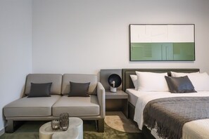 A hotel room with a sofa, a bed, a nightstand, and a wall-mounted artwork. - Modern Studio in MAG City Dubai (Dubai)
