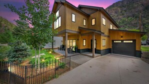 Een modern huis met twee verdiepingen, een garage, een overdekt terras en een aangelegde tuin.