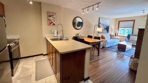 Une cuisine moderne dotée d’un îlot central, d’un coin repas et d’un salon avec un canapé et une fenêtre.