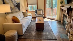 Un salon comprenant un canapé, un fauteuil, une table basse et une cheminée.