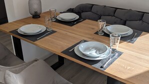 A dining table set with plates, glasses, and cutlery, flanked by a sofa and chairs. - Charming vacation apartment in the heart of the northern Black Forest (Haiterbach)