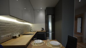 Une cuisine moderne dotée d’un plan de travail en bois, d’appareils électroménagers en acier inoxydable et d’un pare-feu en briques intégré.