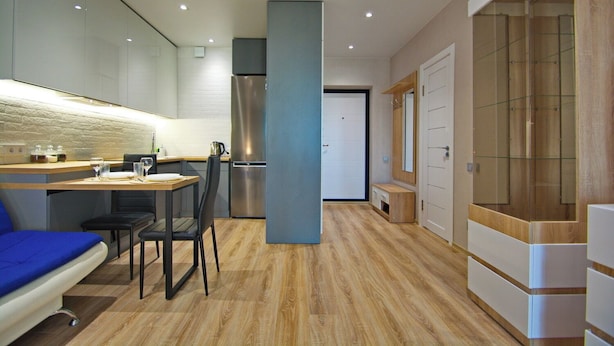 Une cuisine moderne avec un coin repas, un réfrigérateur encastré et un plancher en bois.