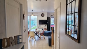 Una cocina moderna con una isla central, un comedor con sillas y una mesa, y vista al exterior a través de una ventana.