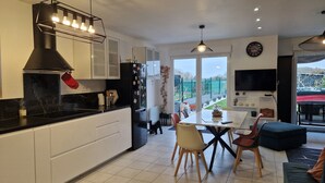 Una cocina moderna con armarios blancos, encimera negra y un comedor con mesa y sillas.