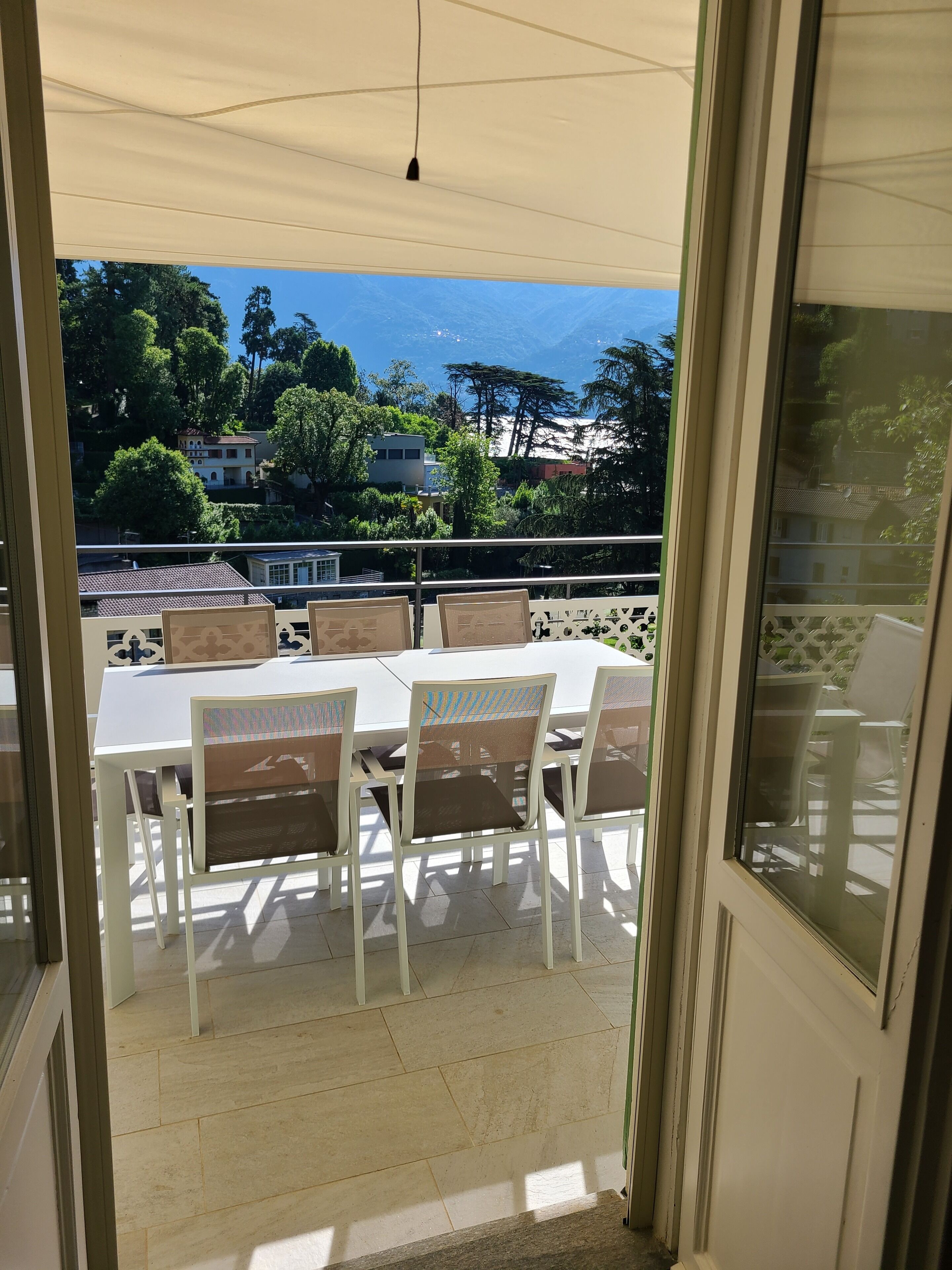 A balcony with a table and chairs, overlooking a residential area with houses and trees.