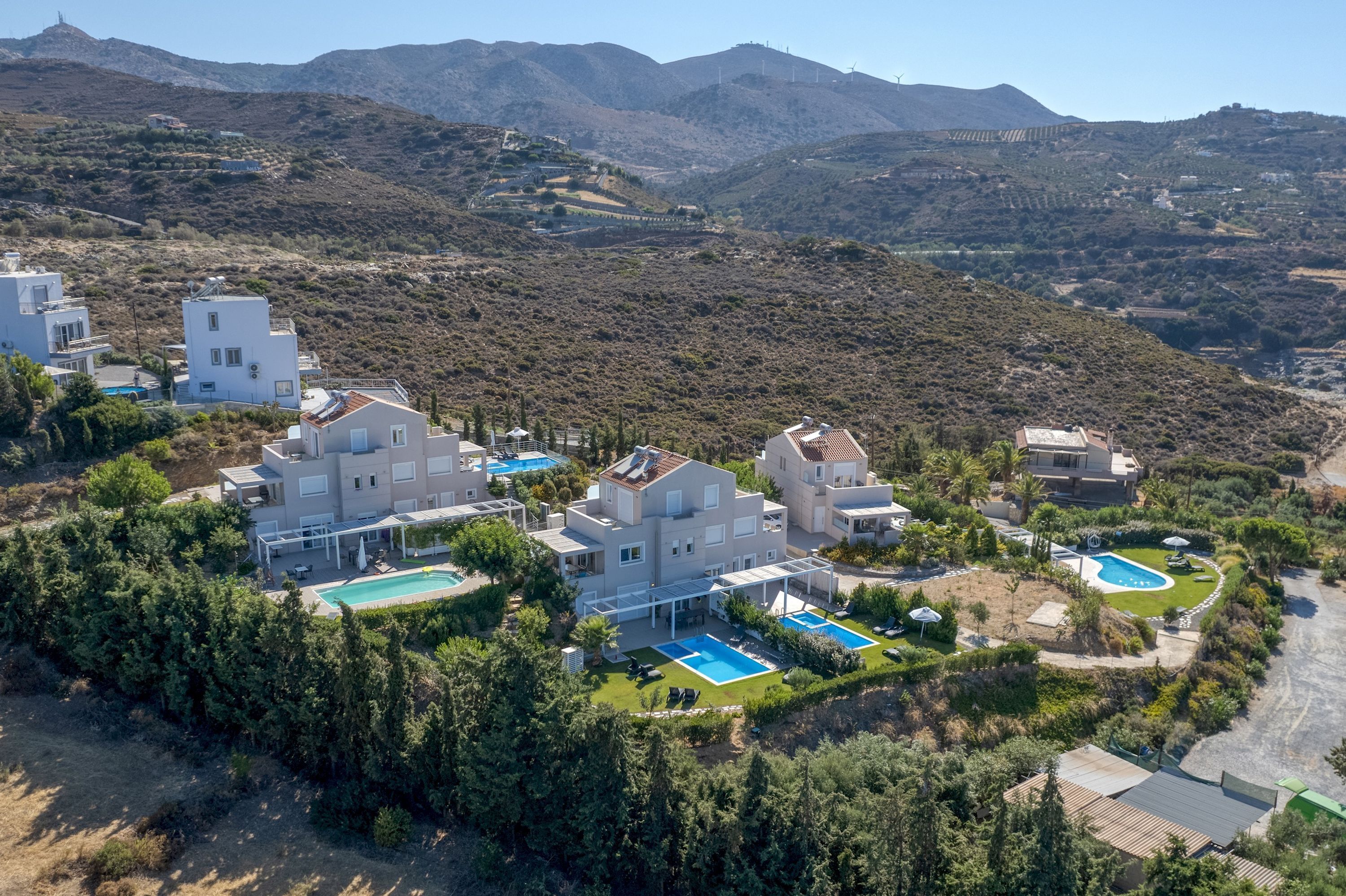 A modern resort with multiple buildings, swimming pools, and lush greenery.