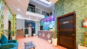 A lobby with a reception desk, a conference hall door, and a staircase. - Hotel The white Sand suites (New Delhi)