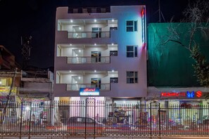 A multi-story hotel with balconies, a visible entrance, and a neon sign indicating it is a hotel.