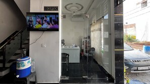 A reception area with a television displaying a show, a staircase, and a parked car. - Shree Radha Vallabh Palace- 800 m from prem mandir (Vrindavan)