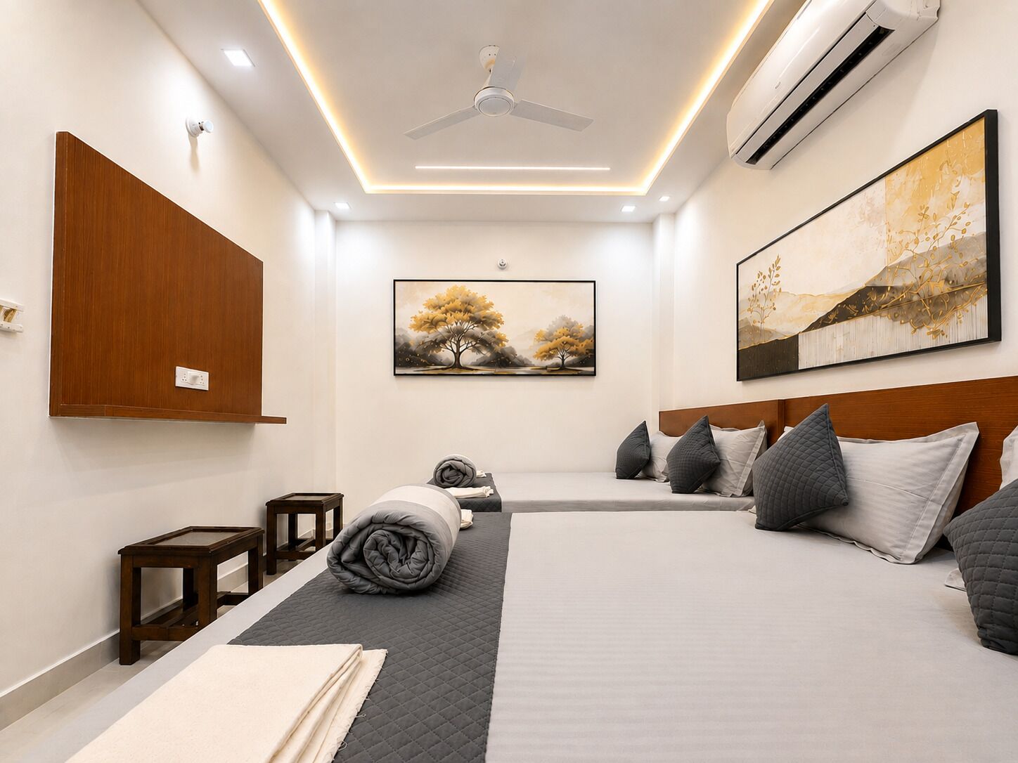 Een moderne hotelkamer met een bed, nachtkastjes, een plafondventilator, een airconditioning en kunst aan de muren.