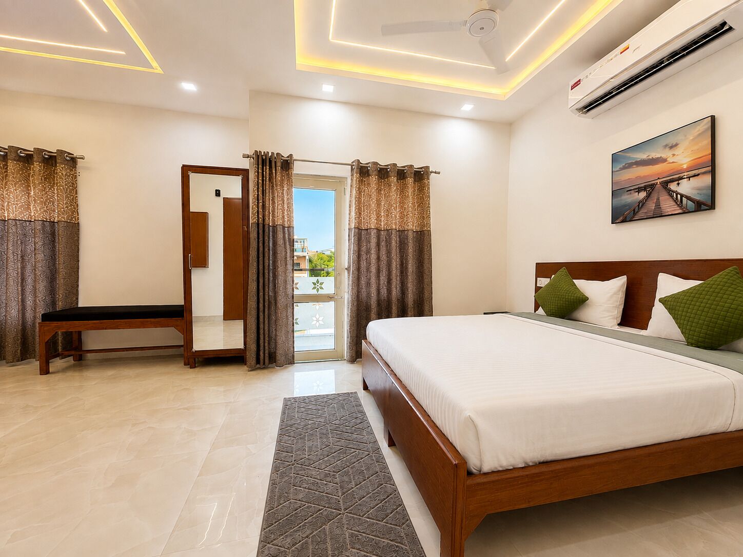 A hotel room with a bed, a bench, a mirror, and a painting on the wall.