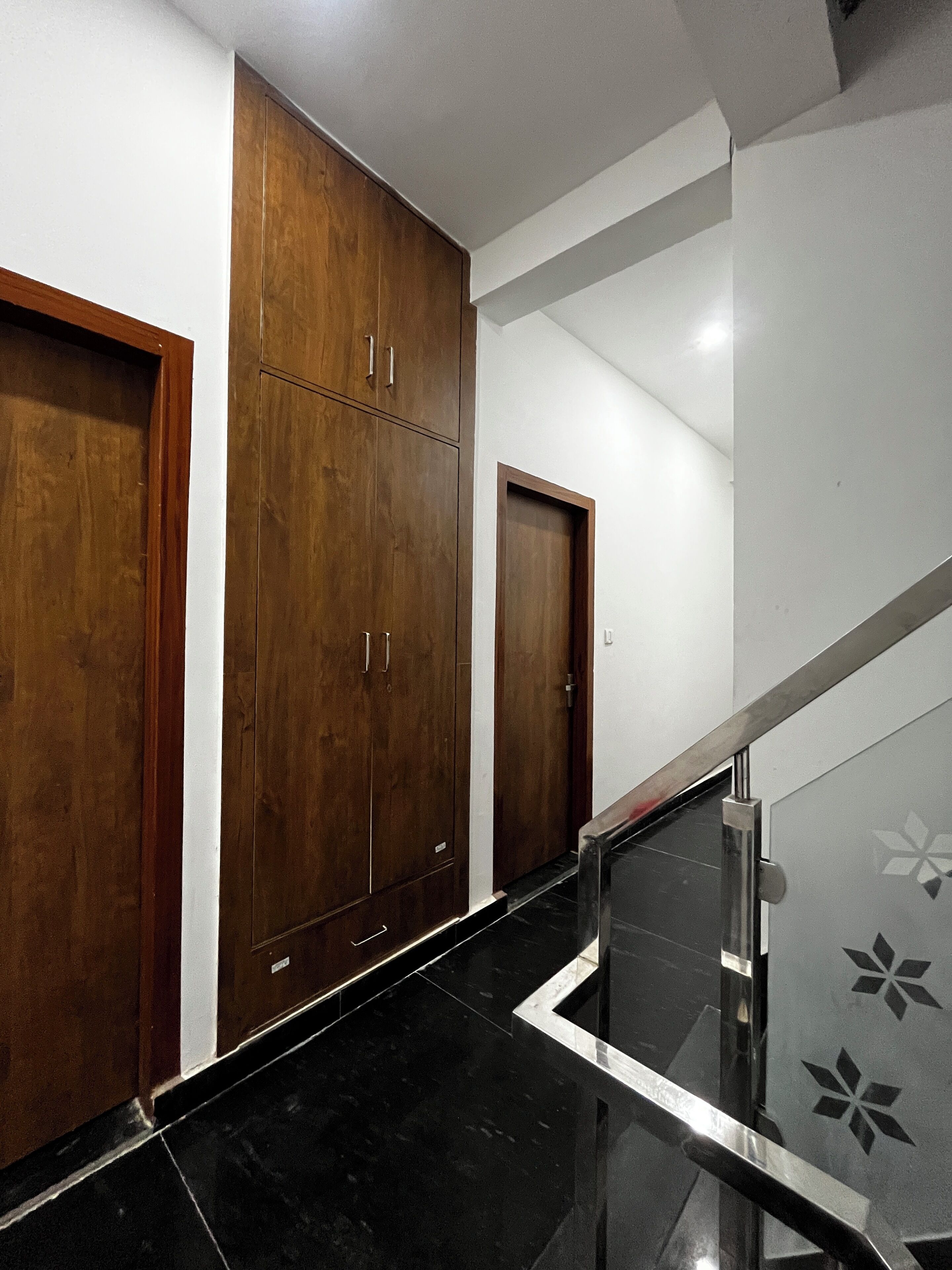Un pasillo con puertas de madera y suelo de mármol negro.