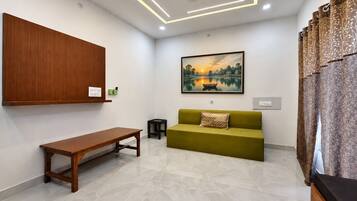 Uma sala de estar moderna com um armário de madeira, um sofá verde, um banco de madeira e uma pintura emoldurada de uma paisagem.