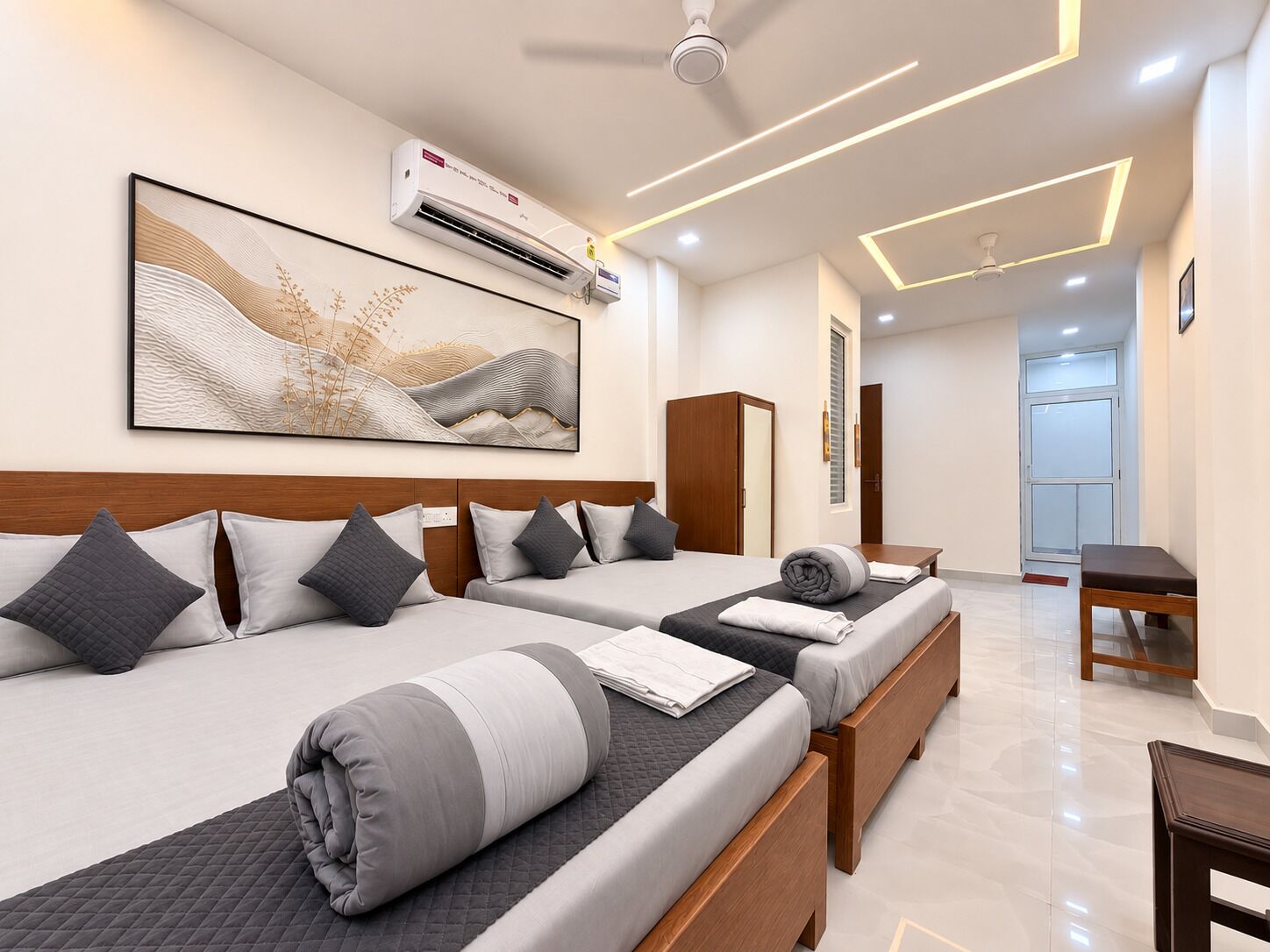A modern hotel room with two beds, a large abstract painting, an air conditioning unit, and a ceiling with recessed lighting.