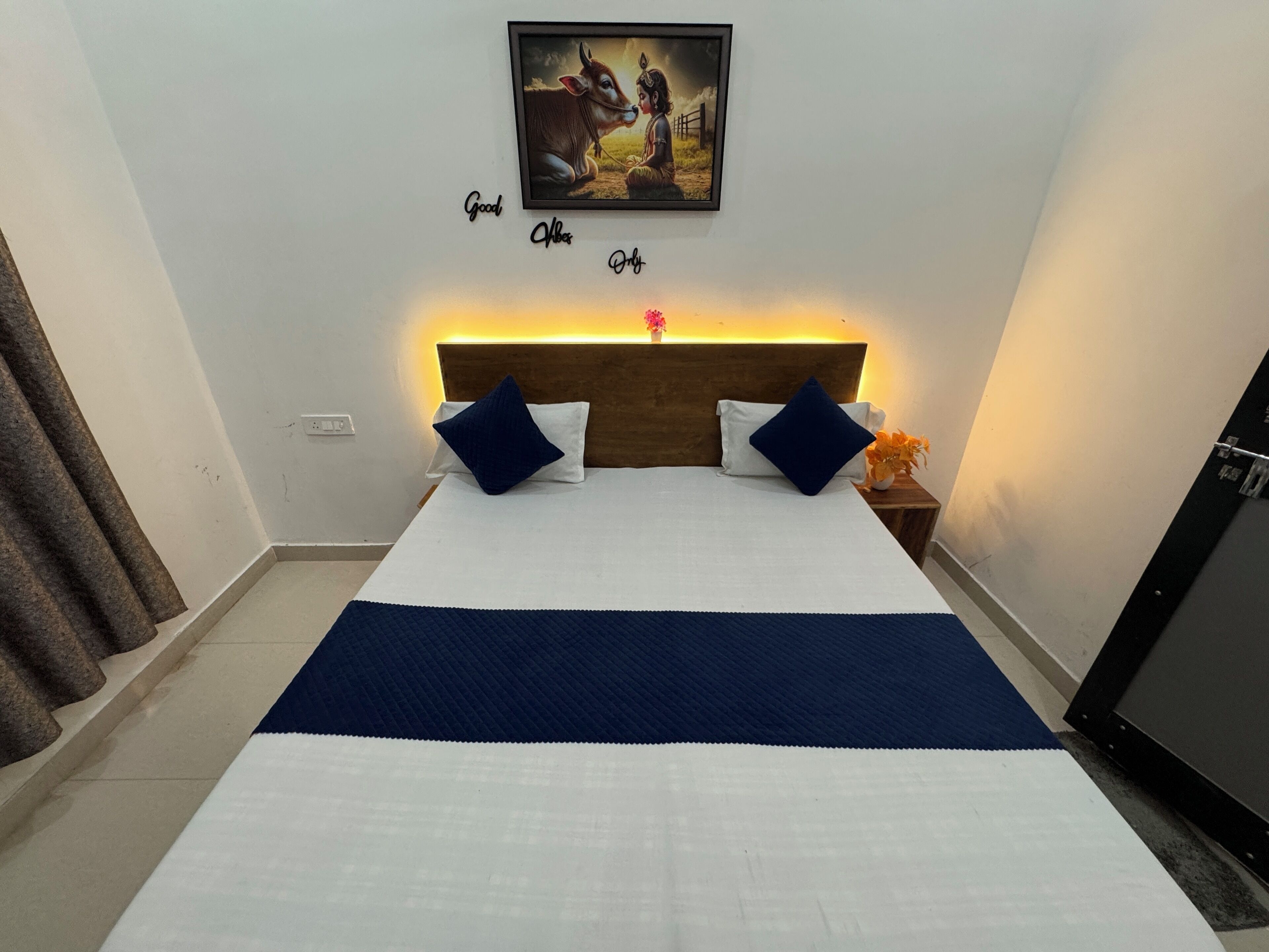 A neatly made bed with a blue and white bedspread, two dark blue pillows, and a wooden headboard.