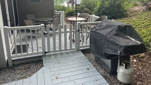 A deck with outdoor furniture, a barbecue grill, and a covered grill area.