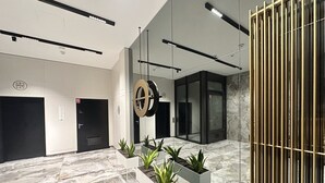 En modern entréhall med marmorgolv, en receptionsdisk, krukväxter och en glasvägg.