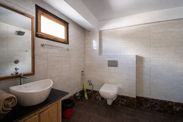 Un baño con lavamanos, inodoro y zona de ducha.