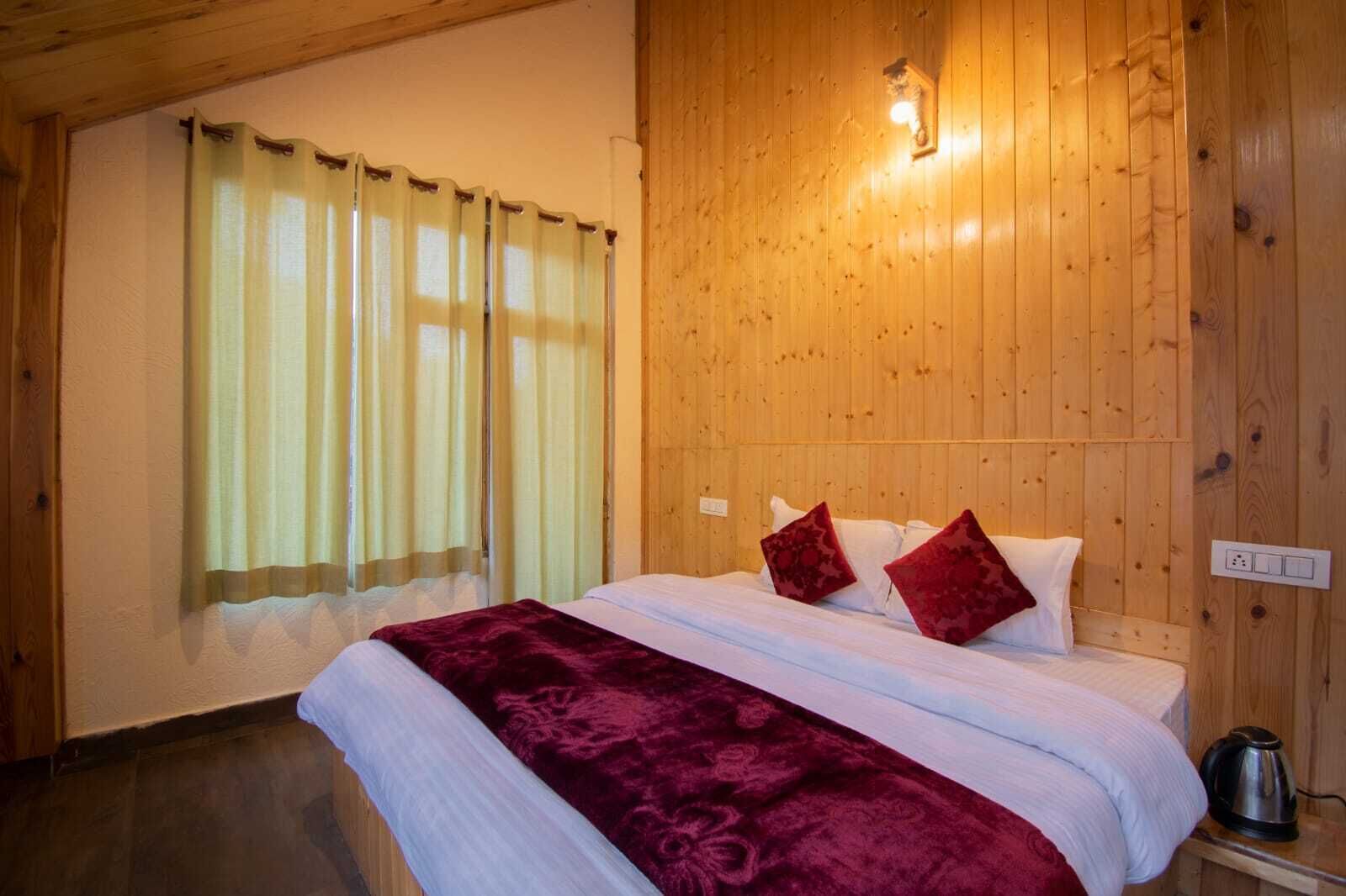 Una habitación con paneles de madera, una cama, cortinas y una tetera sobre una mesa.